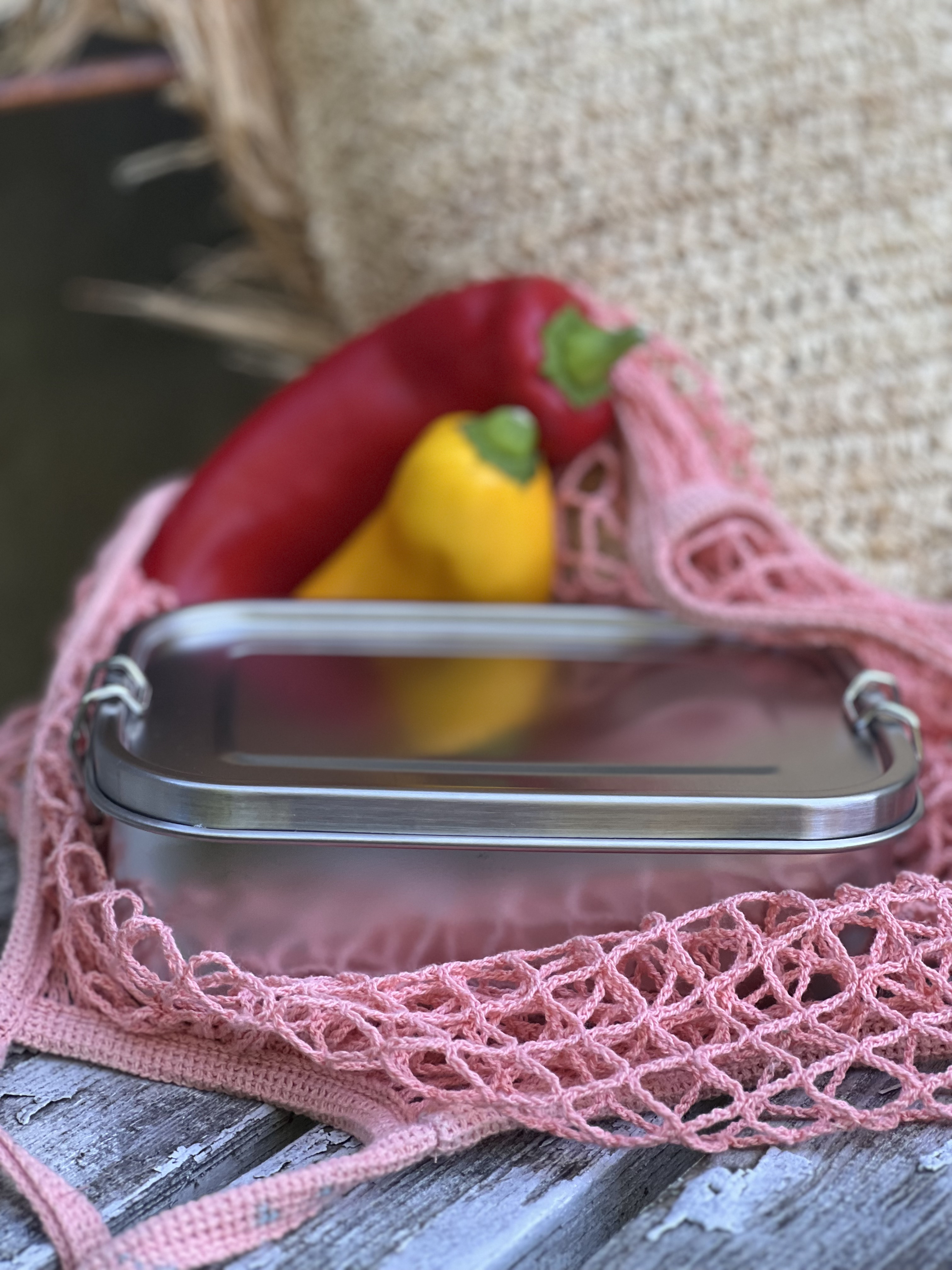 Umweltfreundliche Lunchbox mit Clip aus Edelstahl, dargestellt in einem Einkaufsnetz.