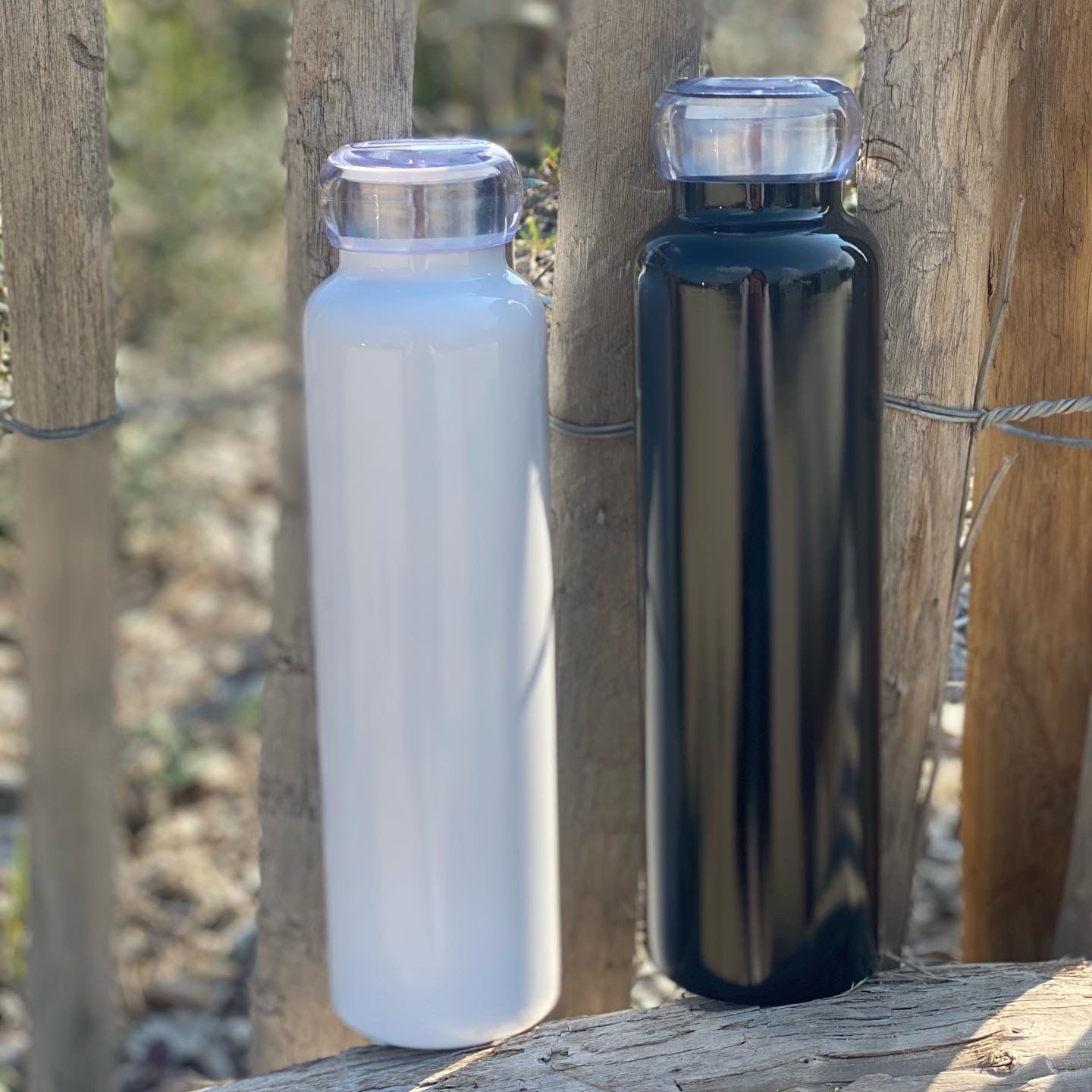 Zwei Vakuumflaschen in schwarz und weiss, die abgerundet sind, 750 ML und mit Schraubverschluss, dargestellt in einem Garten.