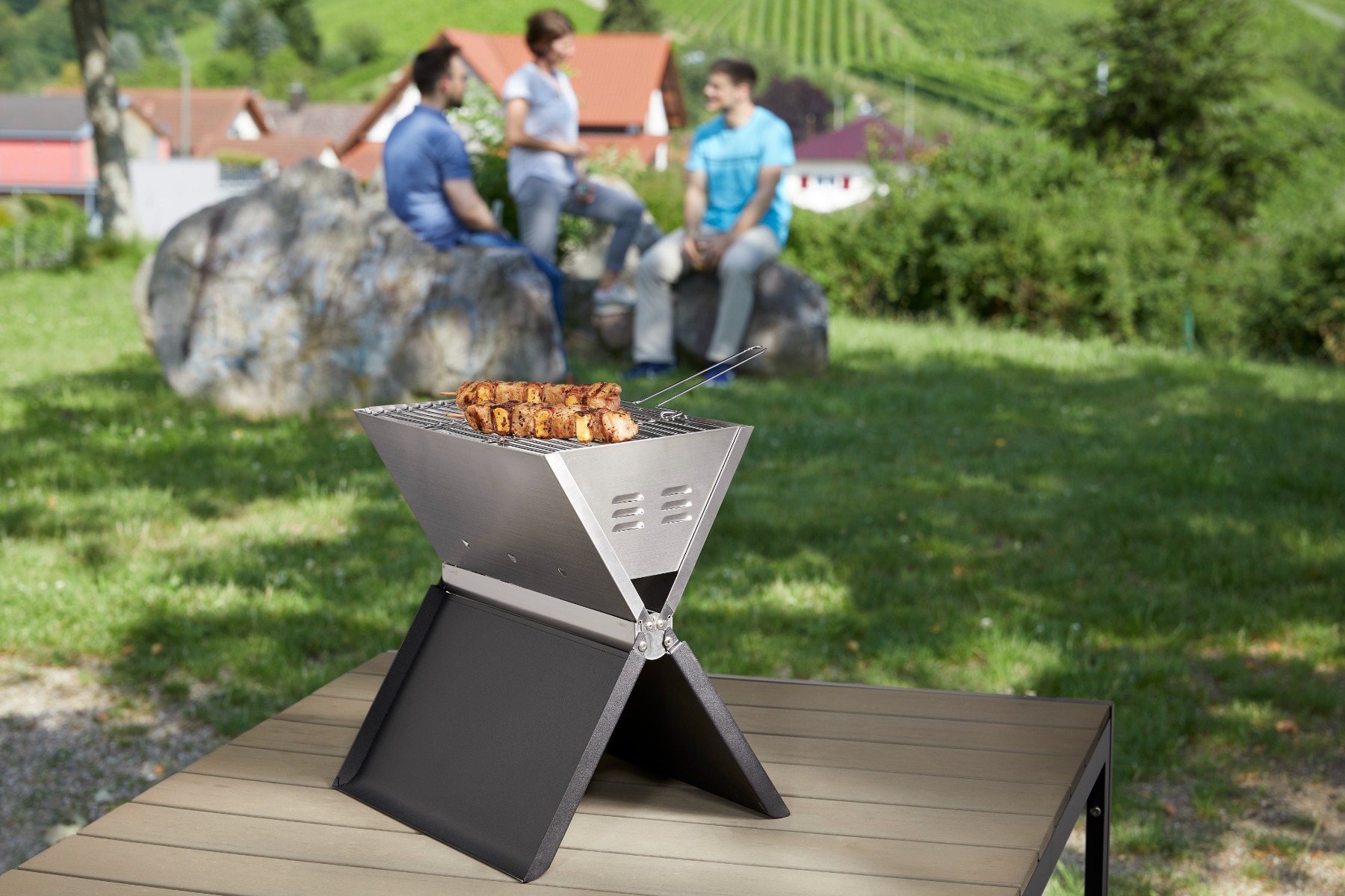 Klappbarer Grill aus Edelstahl, dargestellt im Freien.